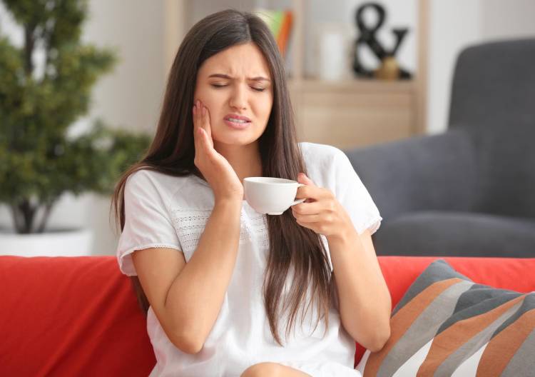 Kobieta odczuwa ból zęba podczas picia gorącego napoju