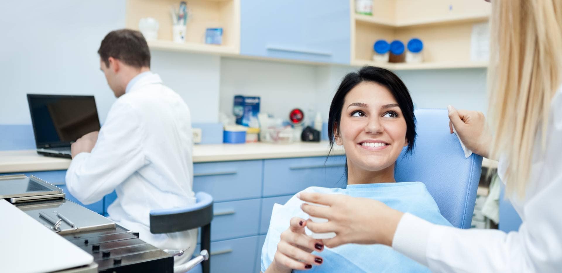 Pacjentka z uśmiechem rozmawia z dentystką w gabinecie stomatologicznym.